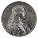 Silver medal of a man in profile to the right with long, curled hair wearing classical arm with…