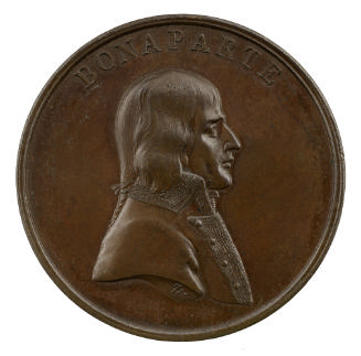 Bronze medal of a man in profile to the right, hair in pigtail with a ribbon, wearing a silk cr…