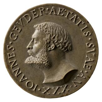 Stone medal of a man in profile to the left with mid length hair and beard