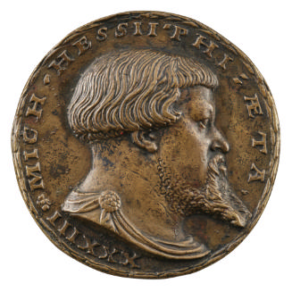 Bronze medal of a man with short hair and a pointed beard, wearing a cloak fastened at the shou…