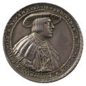 Silver medal of a man wearing a broad hat, pleated shirt, wide-collared cloak, and the badge of…