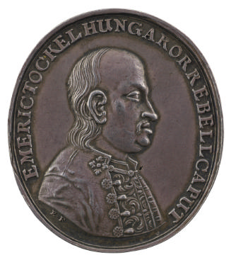 Silver medal of a balding man with a mustache, wearing cloak with decorative fasteners over his…