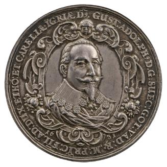 Silver medal of a man with a mustache and goatee, wearing a mantle and large collar