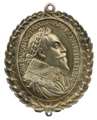 Silver medal of man crowned with laurel, wearing a high decorated tip collar and a harness with…