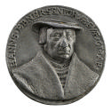 Lead medal of a man wearing hat, hairnet, and chest chains