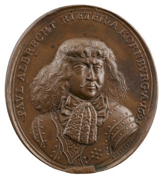 Bronze medal of a man facing front with large tie and bow at neck