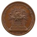 Bronze medal depicting an altar with several objects on top: two classical theatrical masks, a …