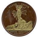 Bronze medal of a bare-breasted woman kneeling in front of a tree trunk, wiping her eyes with h…