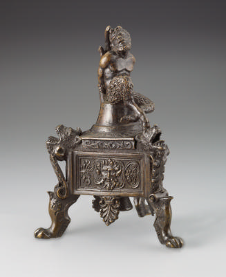 A bronze triangular lamp with a seated satyr who has his arms behind him.  He is bound to a tre…