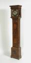 Three-quarter frontal view of long case clock marqueted in various woods 