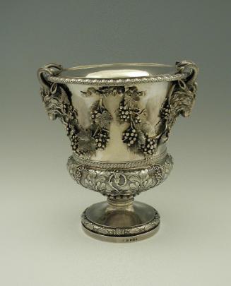 Silver wine cooler with intricate plant designs and rams' heads