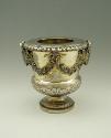 Gold and silver wine cooler with plant designs and rams' heads