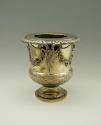 Gold and silver wine cooler with plant designs and rams' heads, side view