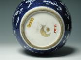 Single blue porcelain covered jar decorated with white floral decorations, bottom of jar.