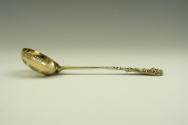 Gilt silver ladle with intricately designed handle and bowl, side view