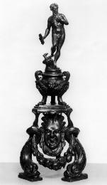 A bronze firedog with a figure of Jupiter.  He has his left hand up to his chest, and has curly…