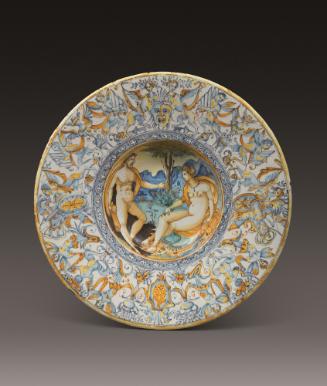 Circular plate with central scene showing a man and a woman in a landscape, surrounded by a bor…