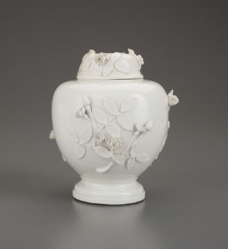 White porcelain tea caddy with floral relief decoration around the body and on the rounded top
