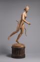 Alternate view of a tinted plaster sculpture of Diana.  She stands on the ball of her left foot…