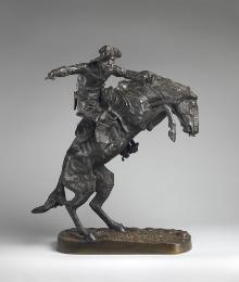 Bronze sculpture of a man wearing a hat while riding a bronco, that is rearing on its hind legs…