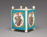 Alternate view of porcelain cubical dish in blue, white, and gold with cupids and trophies