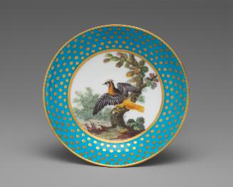 Porcelain saucer in blue and gold with image of bird in tree