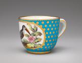 Porcelain cup in blue and gold with image of bird