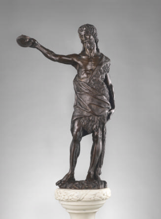 A bronze sculpture of St. John baptizing.  He wears an animal skin cloak.  His right arm is out…