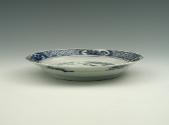 White hard-paste porcelain plate with underglaze blue decoration showing figures in a landscape…