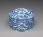 Circular, covered powder box with blue scrollwork decoration