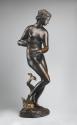 Side view of a bronze sculpture of a marine nymph.  She is in motion and her body is turned to …