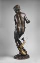 Back view of a bronze sculpture of a marine nymph.  She is in motion and her body is turned to …