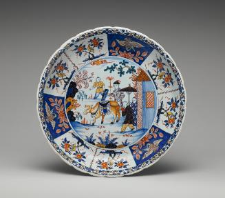 Large circular plate with oriental scene and ornate border in blue and red