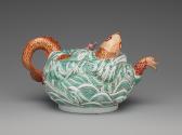 Alternate view of porcelain teapot depicting high relief fish in water in orange and green glaz…