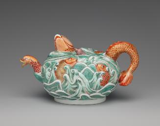 Three-quarter view of porcelain teapot depicting high relief fish in water in orange and green …