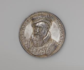 Silver medal of a man in a flat collar and richly decorated armor, wearing a soft cap with a be…