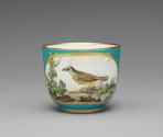 Porcelain cup in blue and gold with image of bird