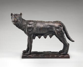 Bronze sculpture of a she-wolf.  Her head is turned to the left