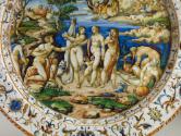 Detail of the center of the dish depicting a scene populated by male and female nude standign a…