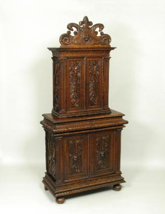 Walnut and pine cabinet with relief carving of masks and vegetal motifs