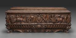 Front view of wooden chest with high relief carving and coat of arms in the center