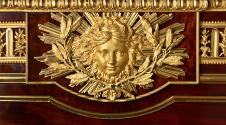 Detail of gilt bronze mask with laurel branches and radiating rays of sunlight
