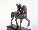 Front view of bronze sculpture of a warrior on horseback.  The warrior figure has his right arm…