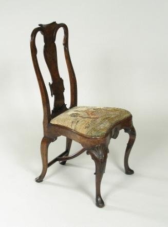 Walnut frame chair with needlepoint upholstered seat with woman standing outdoors