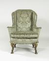 Front view of winged armchair upholstered in light green silk with a damasque motif