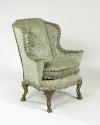 Side view of winged armchair upholstered in light green silk with a damasque motif