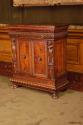 Side view of wood cabinet with relief carving showing figural decoration