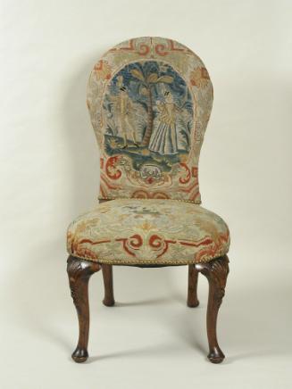 Chair with needlepoint upholstery showing man and woman outside with tree, with vegetal decorat…