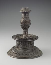 Bronze candlestick featuring intricate motifs throughout.