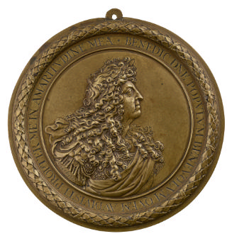 Bronze medal of a man facing right, with long hair, laureate, and wearing Roman armor and imper…